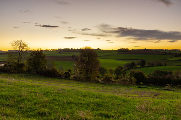 壮观多彩的日出在连绵起伏的山丘上，蜿蜒的道路和农田在林堡南部图片下载