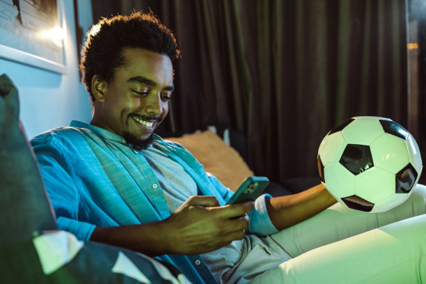 年轻的非洲裔美国男子在家看比赛时看手机图片下载