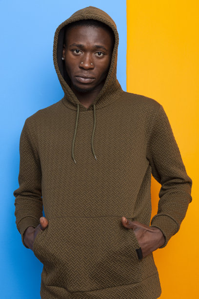 穿着运动衫的黑人模特在蓝色和橙色的墙前拍摄时装。图片下载