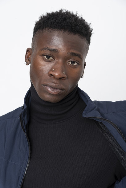 一名黑人男模特穿着牛仔夹克，前面是白色背景。图片下载