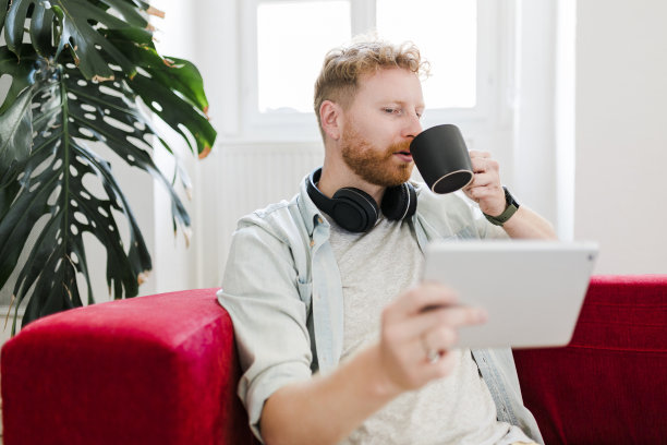 成熟的姜商人在家里喝着咖啡，用平板电脑工作图片下载