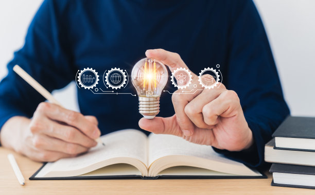 学生手持明亮的灯泡，阅读书籍或教科书。成功的教育理念，学习和学习。商务人员技能培训课程。知识与认知概念图片下载