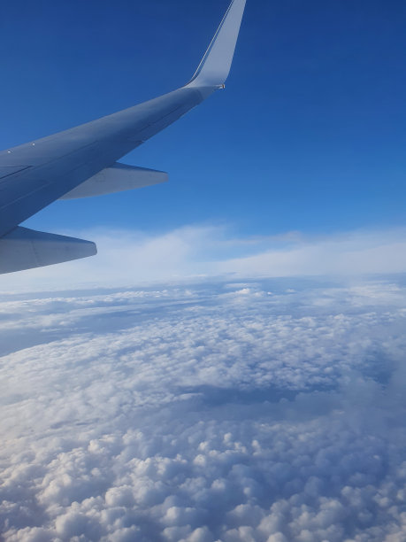 飞机的翅膀飞过云层和晴朗的蓝天。图片下载
