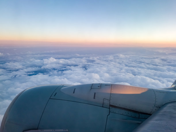 日落时，飞机在云层和晴朗的蓝天上飞翔。图片下载