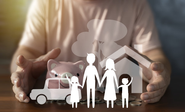 男人的双手保护着家里的人物，房子，汽车，桌上成堆的硬币。为了保护家庭开支，为家庭的未来存钱图片下载
