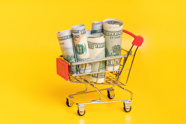 购物车里装满了现金，黄色背景的美元。商业，金融，经济概念。图片下载