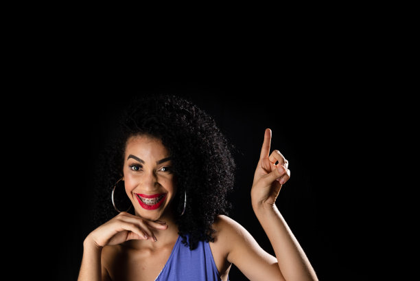 年轻美丽女子的肖像，坐着，指着上面，穿着蓝色的衣服。图片下载