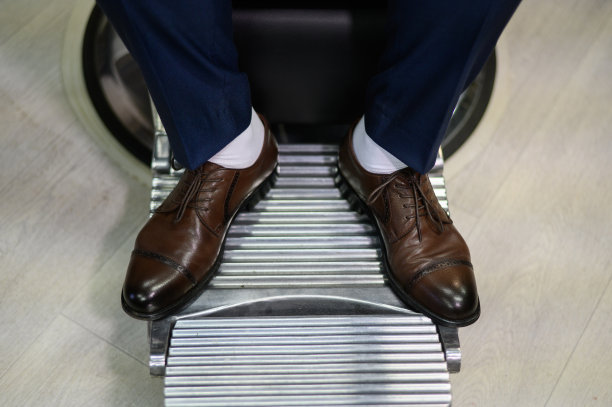 一个穿着皮鞋的男人坐在理发店的扶手椅上。男性自信。图片下载