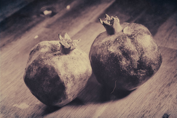 木桌上放着两个不新鲜的红石榴图片下载