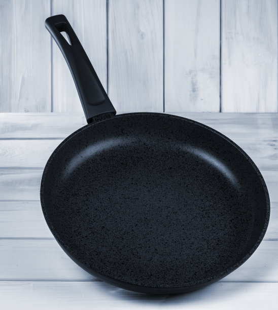 煎锅与不粘涂层对浅蓝色木材纹理的背景。图片下载