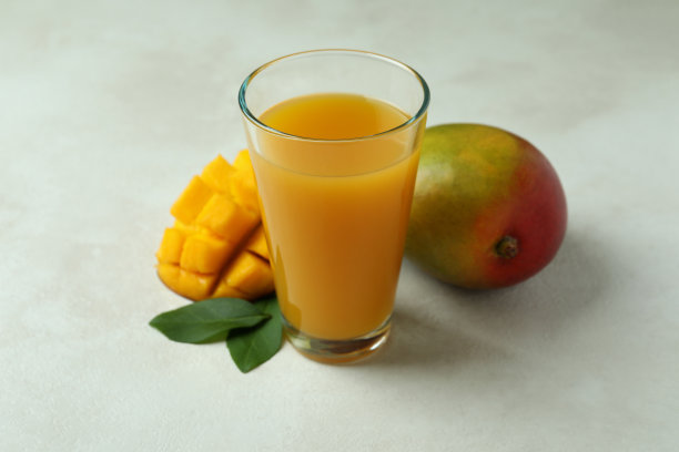 成熟的芒果和果汁放在白色纹理的桌子上图片下载