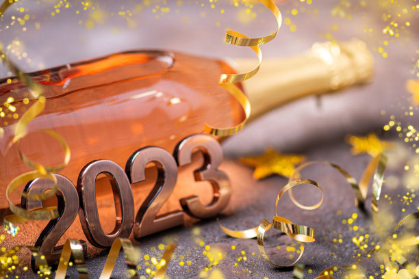 2023年新年快乐背景。新年卡片与一瓶香槟，节日装饰，灯，礼物。2023年新年喜庆背景图片下载