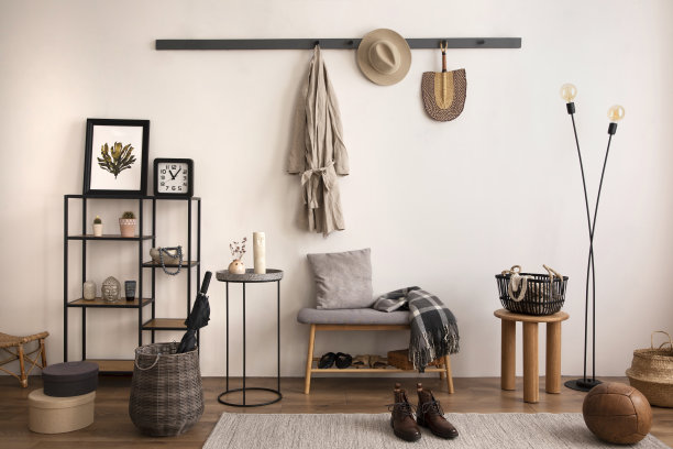 灰色长凳、黑色沙发、衣架和台灯构成舒适的时尚入口。米色墙。家居装饰。模板。图片下载