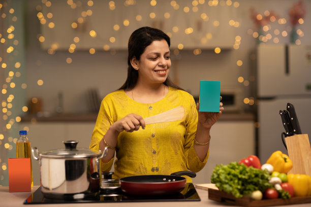 印度妇女在厨房做饭时享受的肖像。库存图片图片下载