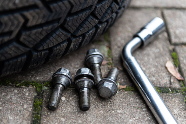 四个二手车车轮螺栓掉在地上，新的冬季轮胎和扳手。图片下载