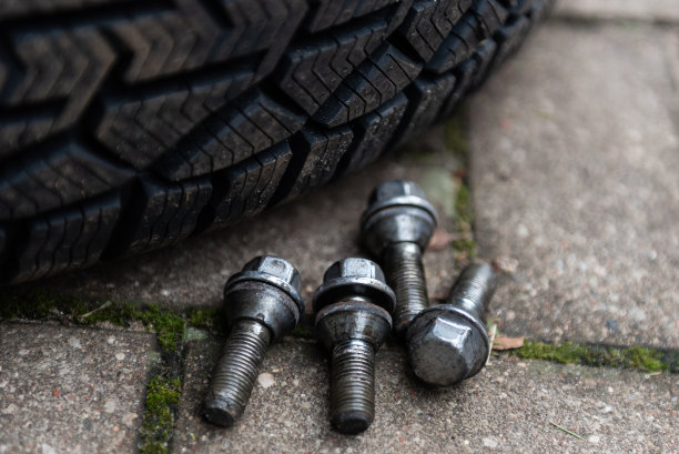 四个二手车车轮螺栓掉到地上和新的冬季轮胎。图片下载