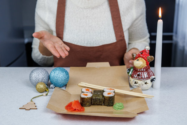 日本红鱼卷，装在敞开的纸板箱里。女孩用筷子吃寿司。表装饰图片下载