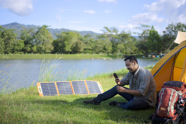 男子在户外露营，太阳能电池板正在充电。图片下载
