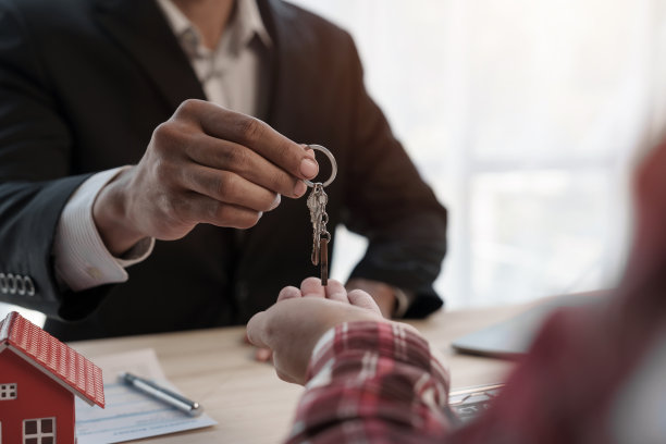 给一个房子钥匙，信用审批人，西装革履的商人和房子玩具模型模型房屋贷款抵押批准概念。签订合同后图片下载