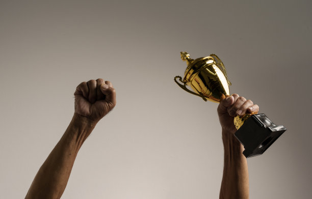 高举奖杯的老人举起双手。孤立的，靠近点。图片下载