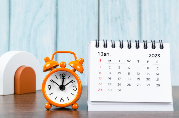 2023年1月的每月台历，供组织者规划2023年，木制桌子上有闹钟。图片下载