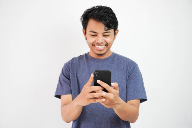 英俊的微笑或快乐的亚洲年轻男子休闲服装海军t恤手持智能手机聊天或视频通话在白色孤立的背景。图片下载