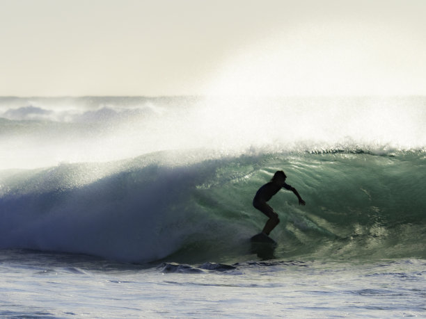 在海浪中冲浪的人的剪影图片下载