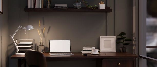 现代黑暗的办公室工作空间在晚上与笔记本电脑模型在桌子上靠黑墙。图片下载