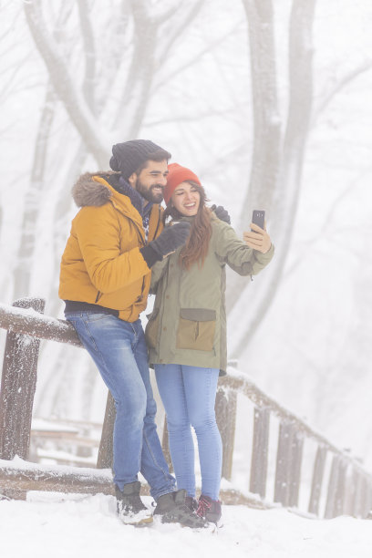 在大雪纷飞的冬日里，一对情侣在户外自拍图片下载