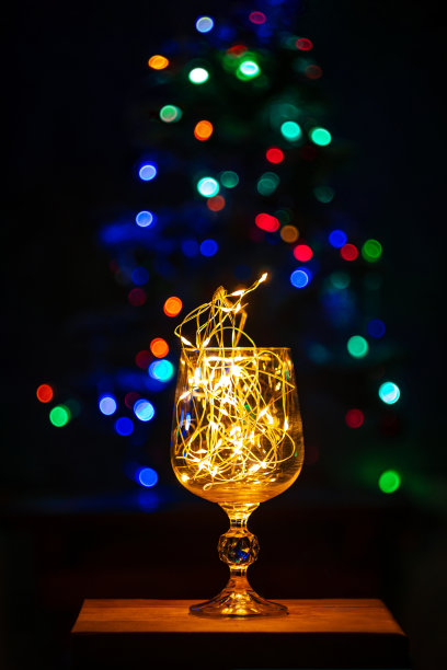 水晶酒杯装饰着发光的花环新年圣诞表散景光背景垂直屏幕保护程序图片下载