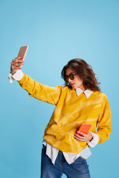 年轻时尚的漂亮女孩的肖像，穿着休闲服，在蓝色背景上孤立地自拍图片下载