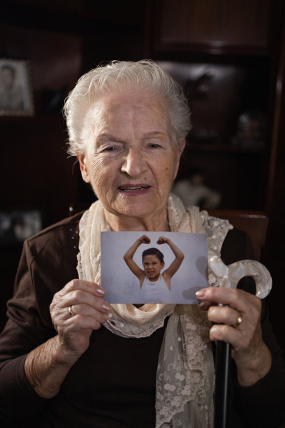 奶奶微笑着，自豪而快乐地展示着孙子的旧照片。家庭和后代观念。图片下载