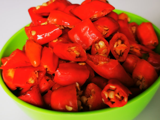 一束印尼红辣椒(辣椒)，切碎后放入白色背景的绿色碗中图片下载