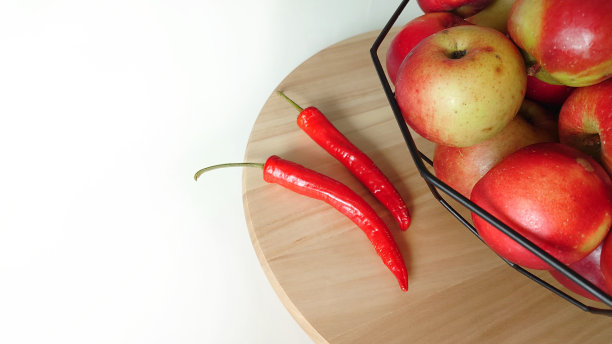 白色桌子上的果盘上放着苹果和辣椒图片下载