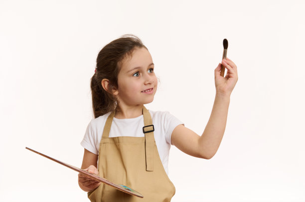有灵感的小艺术家，穿着米色围裙的天才女婴，拿着彩色油画颜料和画笔的木制调色板图片下载
