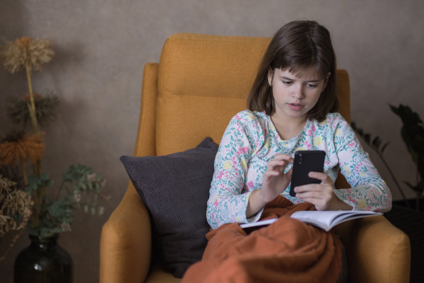 女孩把书放在腿上用智能手机图片下载