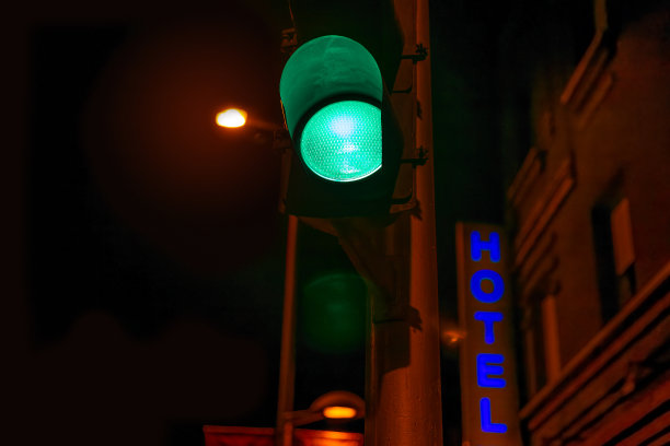 夜晚的绿色交通灯对着蓝色的酒店霓虹灯图片下载