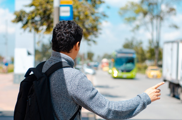男子在街上等待公共汽车的后视图图片下载