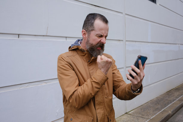 一个拿着智能手机站着的男人。图片下载