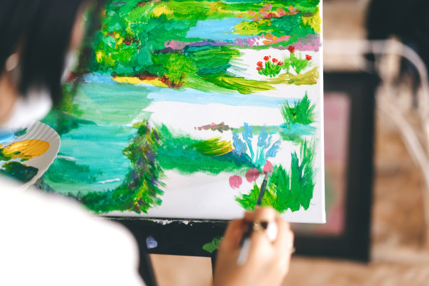 在工作坊艺术课上，一位女士在画布上作画图片下载