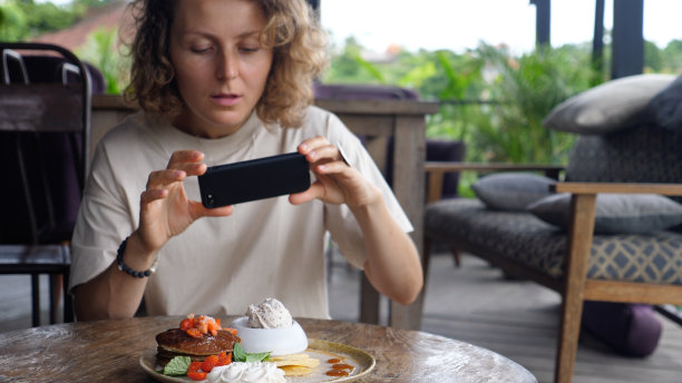 在社交网络上分享午餐照片。一位女性美食博主正在拍摄她健康美味的素食煎饼。她受到追随者的鼓舞。图片下载