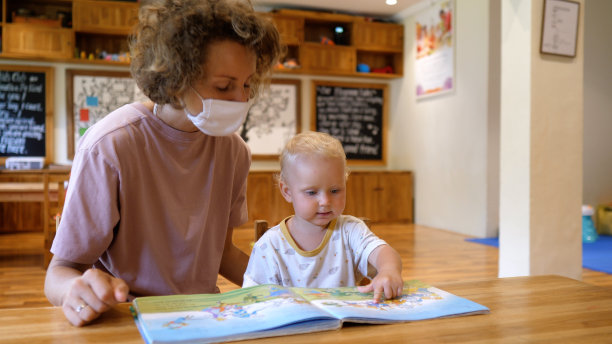 一位年轻的单身母亲教她年幼的孩子享受阅读。他们学会寻找有合适动物的图片。真诚地欢呼和鼓掌。儿童教育活动。图片下载