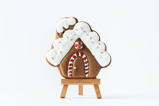 圣诞姜饼屋形状的饼干，白色背景上有白色的雪花糖衣。自制节日传统饼干。圣诞快乐图片下载