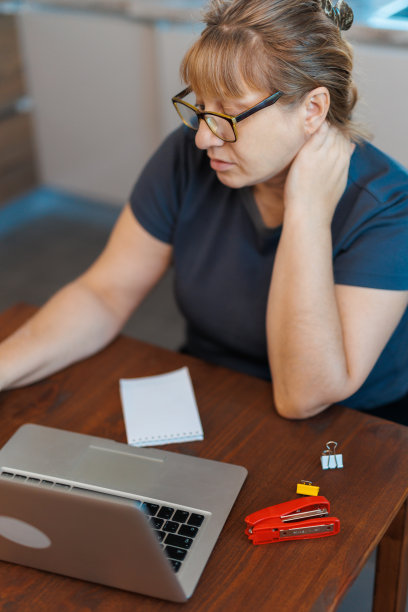 疲惫成熟的金发女性自由职业者在家工作，使用笔记本电脑，坐在厨房，复制空间。有压力的高级女士坐在电脑前记笔记图片下载
