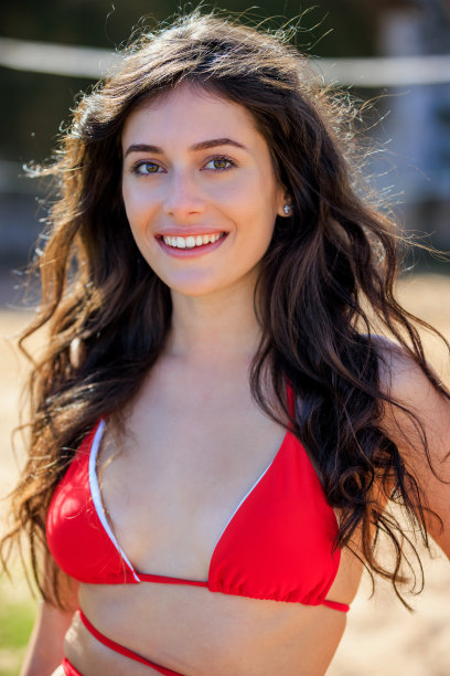 穿着红色比基尼上衣，长棕色头发的漂亮女人肖像，对着镜头微笑图片下载