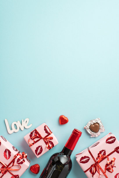 情人节的概念。顶部查看礼盒在包装纸与亲吻嘴唇图案酒瓶巧克力糖果铭文爱孤立的浅蓝色背景与复制空间垂直照片图片下载