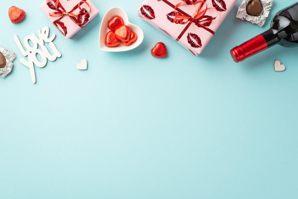 情人节的概念。礼盒的顶部视图照片心形盘子与巧克力糖果酒瓶和铭文爱你在孤立的粉彩蓝色背景与空白图片下载