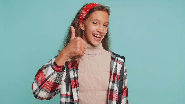 快乐的少年小孩女孩小孩赞许地看着摄像机竖起大拇指，就像一个积极的信号图片下载