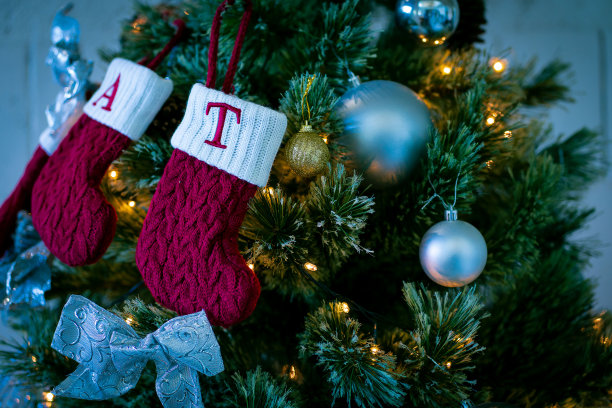 圣诞树上装饰有吊袜带，装饰人头。一棵美丽的圣诞树，上面装饰着美丽闪亮的装饰品和许多礼物。图片下载