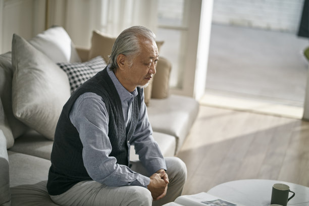 一个悲伤的亚洲老人独自坐在家里的沙发上图片下载